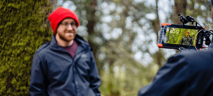 Hemophilia A patient, Billy Eshleman, in a red hat smiling and being interviewed in the woods.