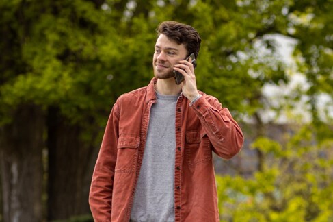 Hemophilia A patient Rex Herald talking on a phone with trees in the background.