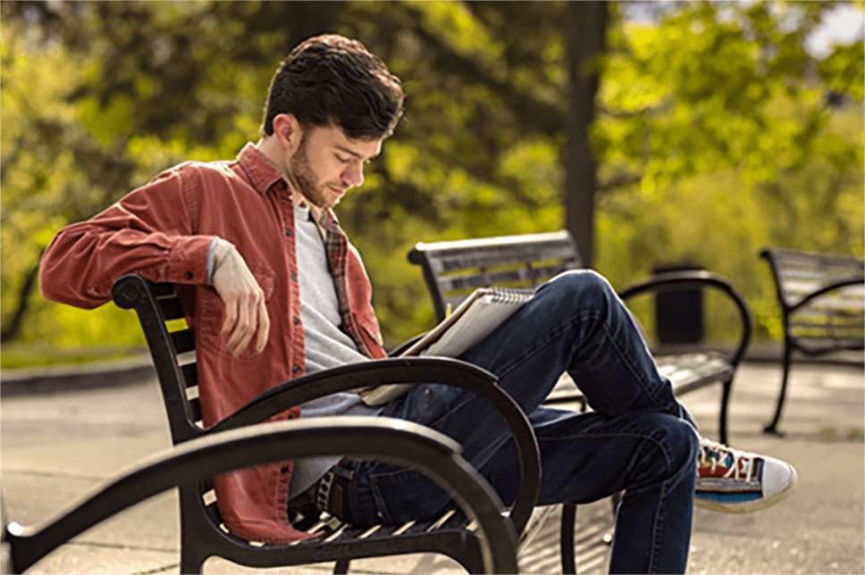 Hemophilia A patient, Rex Herald, sitting on a bench in a park with a book.