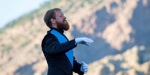 Hemophilia A patient, Billy Eshleman, lifting his right hand, looking sideways with a mountain in the background.