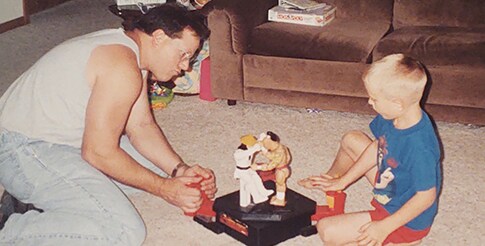 A retro image of Hemophilia A patient, Billy Eshleman, and his father sitting on the ground playing with a toy.