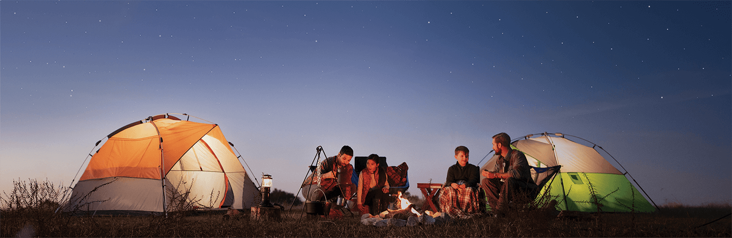 A family camping sitting around a bonfire 